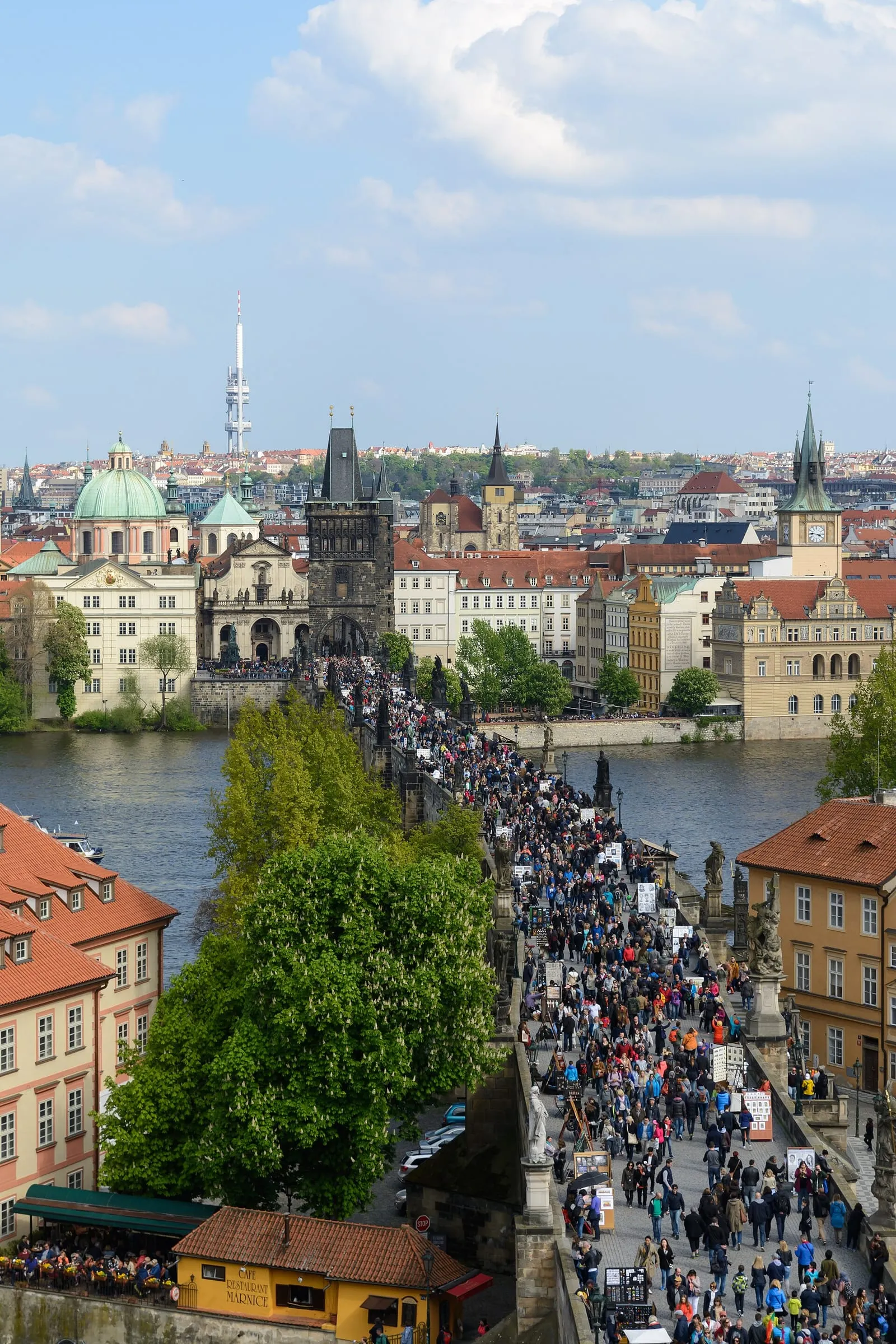 The rough cobbled deck of Charles Bridge arching between its stone towers at dawn