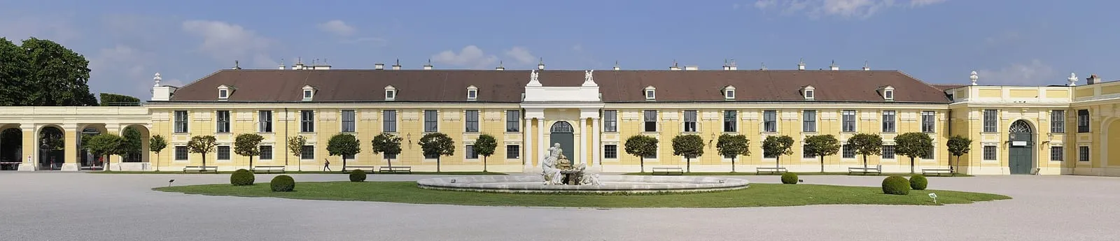 The long yellow facade of Schönbrunn Palace above its level gravel forecourt