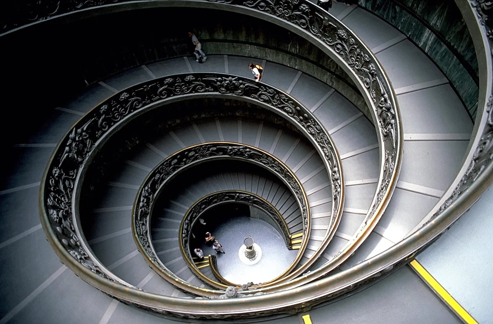 Una lunga galleria dei Musei Vaticani con un pavimento in marmo liscio che si estende tra i visitatori